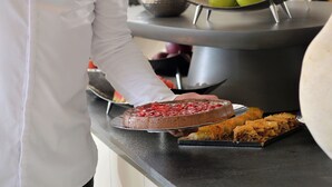 A chef in a white uniform preparing food on a counter with various dishes and fruits. - Althea Resorts (Xylokastro-Evrostina)