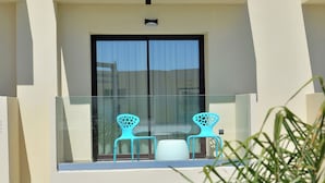 A modern building with a balcony featuring two blue chairs and a white table. - Althea Resorts (Xylokastro-Evrostina)