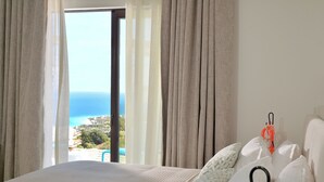 A hotel room with a bed, white bedding, a view of the ocean, and a balcony. - Althea Resorts (Xylokastro-Evrostina)