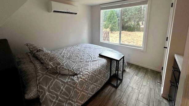 Een slaapkamer met een bed, een raam en een klein tafeltje.