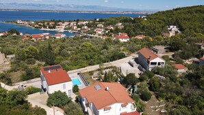 An aerial view of a coastal residential area with houses, a swimming pool, and a view of the sea and mountains in the background. - Charming Apartment Secret Garden (Lukoran)