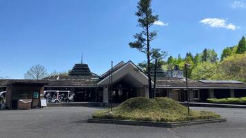 Un edificio con techo inclinado, un área de estacionamiento pequeña y un espacio verde con un árbol.