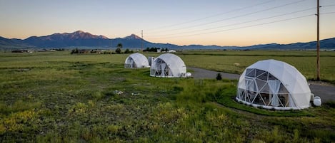 Estructuras de domos geodésicos en un entorno rural, con montañas al fondo.