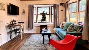 A cozy living room with a fireplace, a television, a Christmas tree, and a red chair.