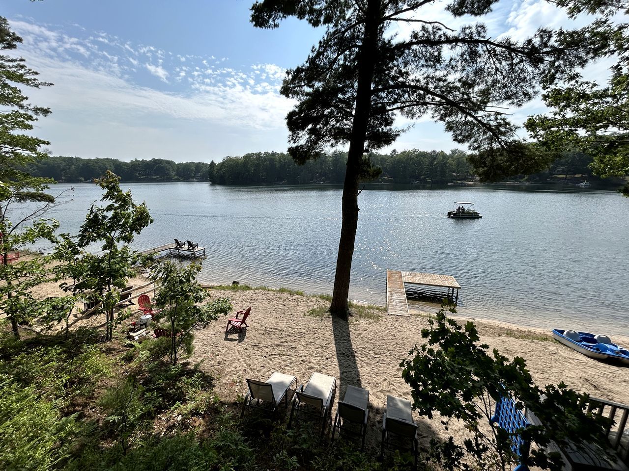 Une vue sur le lac avec un quai, des chaises et un bateau.