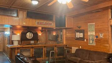 Un intérieur en bois avec un coin bar, des meubles en cuir et un ventilateur de plafond.
