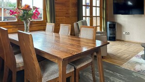 Un interior de fusta amb una taula de dinar, cadires, un televisor i una finestra amb cortines.