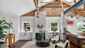 Een moderne woonkamer met een open haard, houten balken en grote ramen.