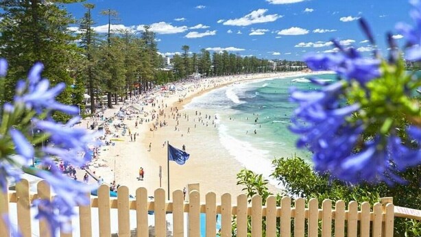 Een strand met mensen, een vlag en een houten omheining.