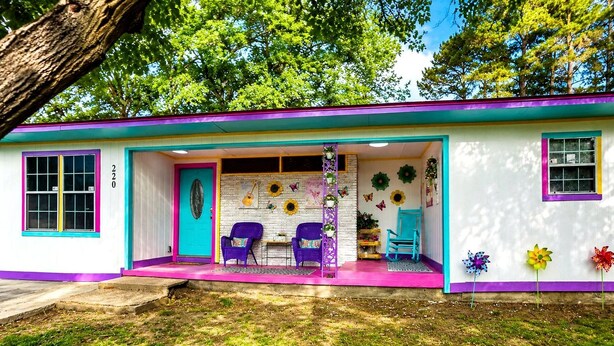 A colorful house with a porch, two chairs, and a small table.
