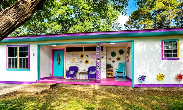 A colorful house with a porch, two chairs, and a small table. - Girls Just Wanna Have Fun: Unique Vacation Rental in Lone Star, Texas (Lone Star)