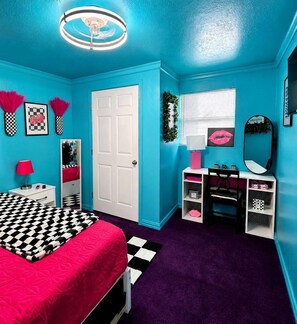Une pièce comprenant un lit, un bureau, une chaise, un miroir et une porte.