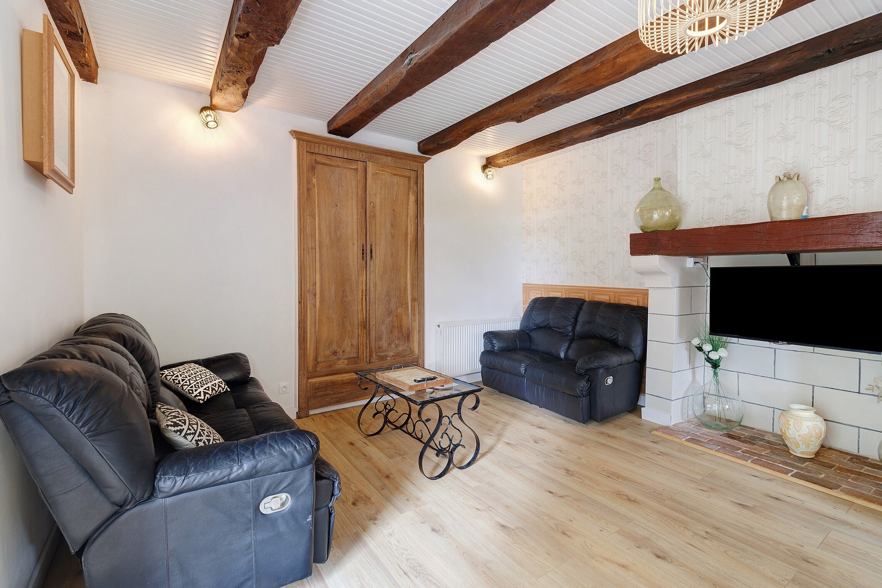 Una sala de estar con sofá, mesa de centro, chimenea y vigas de madera en el techo.