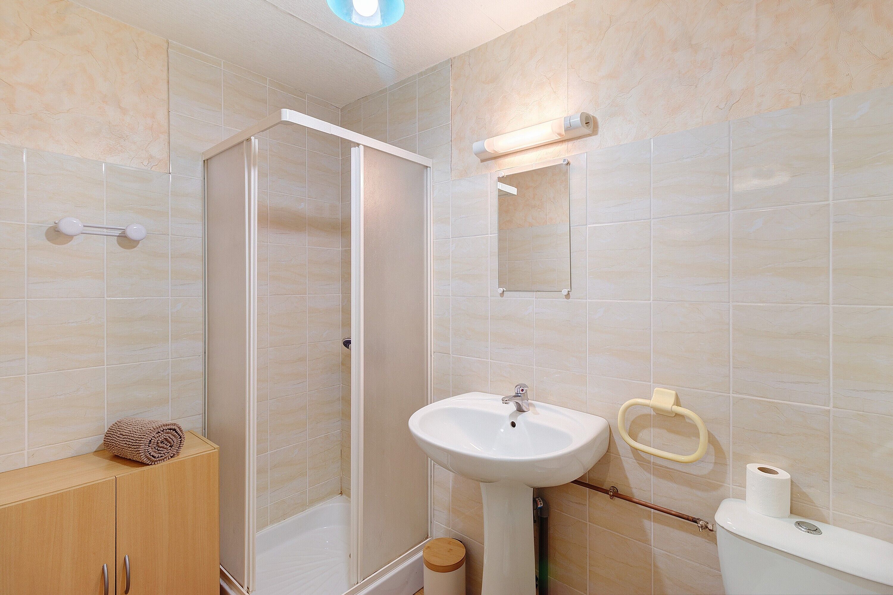Een badkamer met een douche, wastafel, toilet en een handdoekhouder.