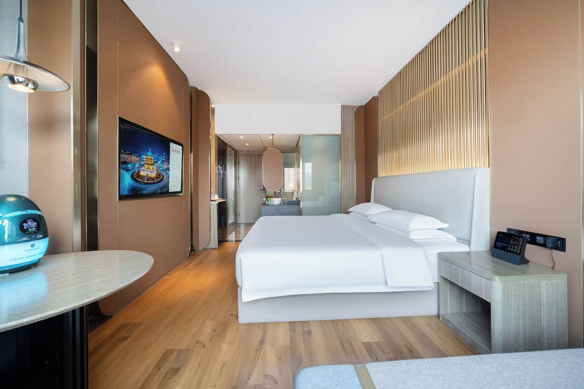 Una habitación de hotel moderna con una cama grande, una mesita de noche y un escritorio con una silla.