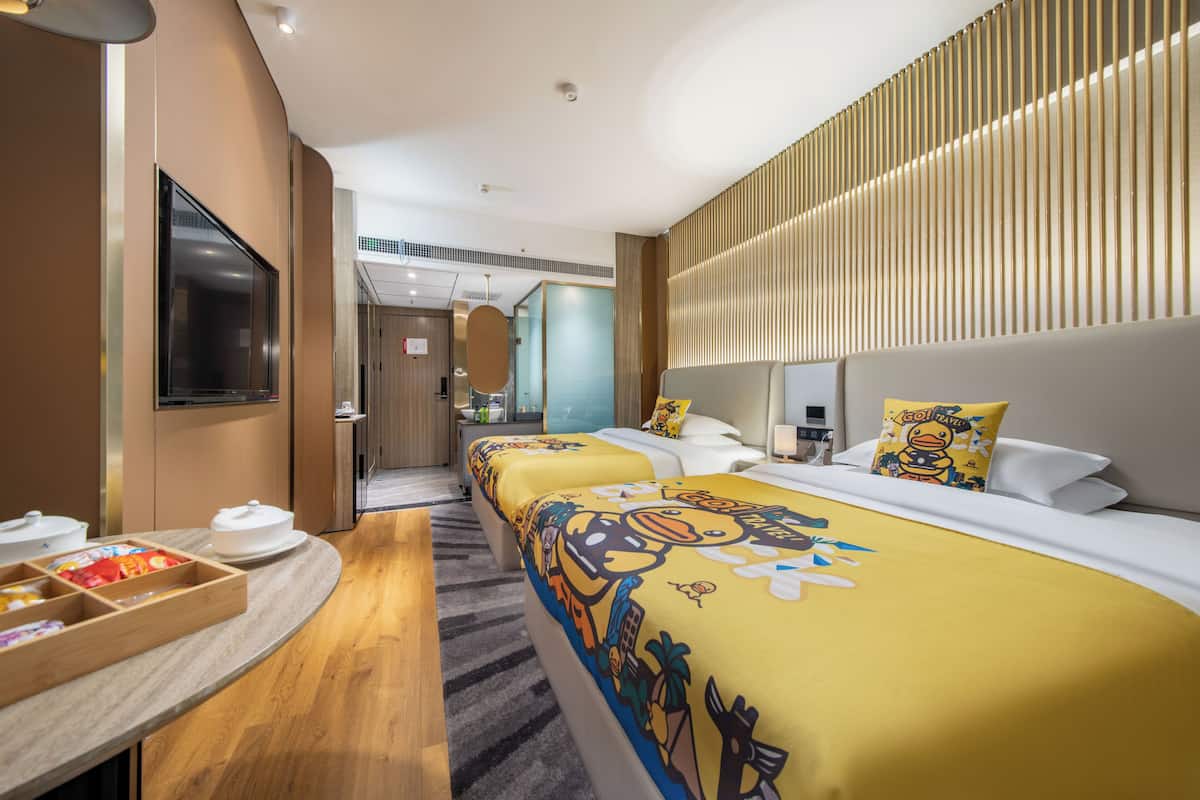Una habitación de hotel con cama, mesita de noche y televisor montado en la pared.