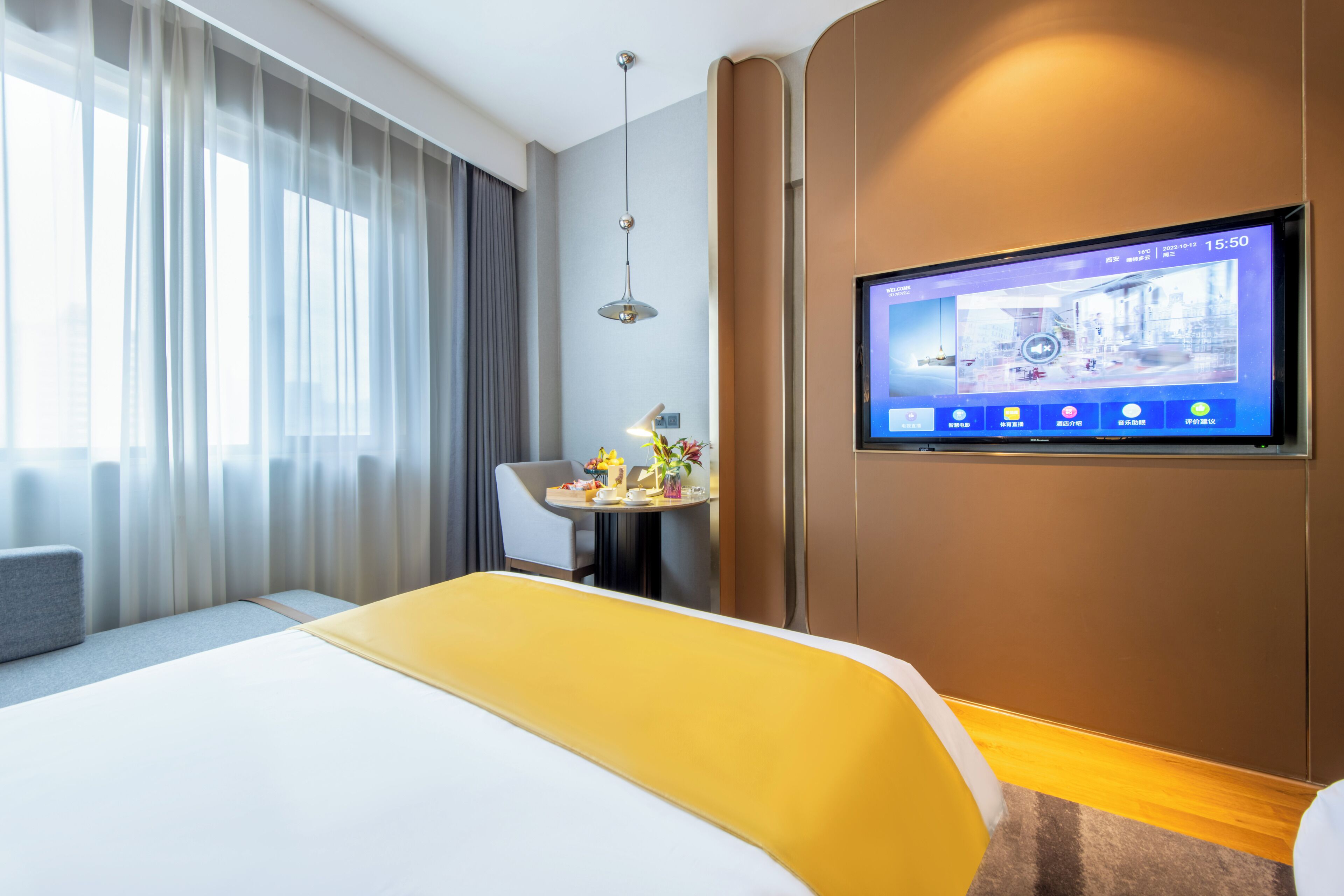 Habitación de hotel con cama, televisor en la pared, escritorio con lámpara y ventana con cortinas.