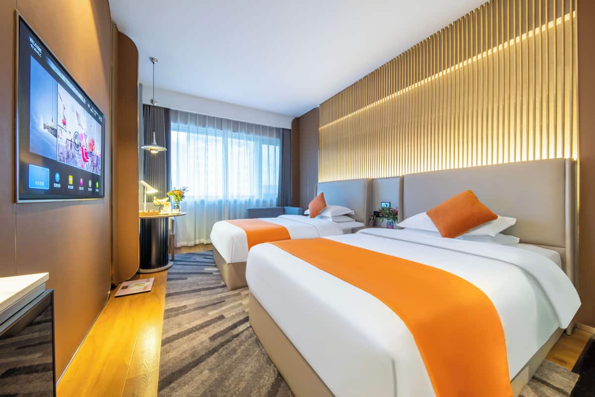 Una habitación de hotel con dos camas, televisión, escritorio y un ventanal grande.