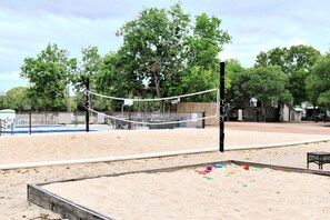 A sandy volleyball court with a net, surrounded by trees and a fence. - Peaceful Tented Cabin by the Geronimo Creek - An Amazing Nature Escape in Seguin, Texas (Seguin)