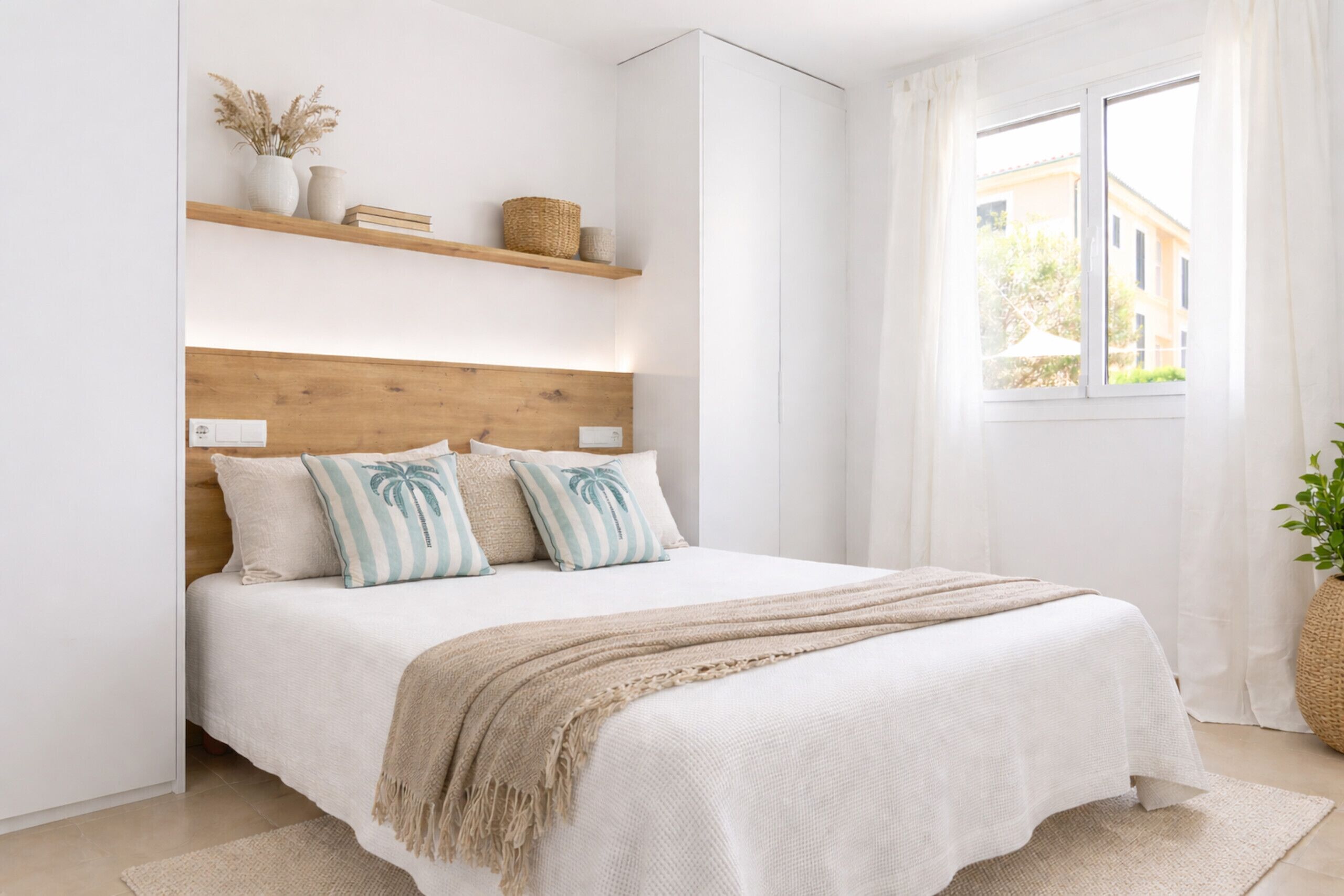 Una camera da letto con testiera in legno, un letto con biancheria bianca, una coperta beige e una finestra con tende.