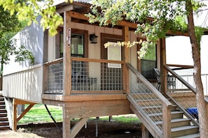 Une terrasse en bois avec une rambarde en métal, un escalier et une plaque indiquant le numéro de l’unité.