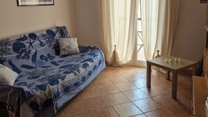 Quarto com cama, mesa e janela com cortinas.