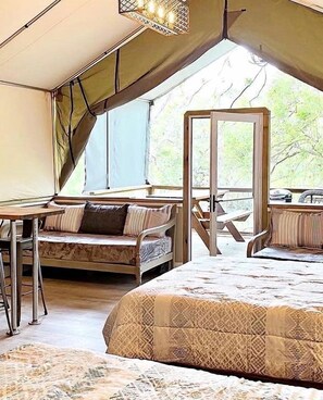 A tented room with a bed, a table, and a chair. - Family Escape by the Water: Fully Equipped Waterfront Tented Cabin Getaway in Cibolo, TX (Cibolo)