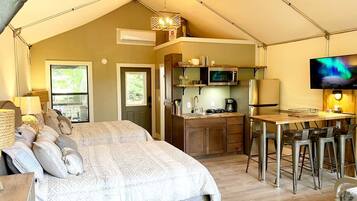 Ett tältliknande boende med en säng, ett litet kök, en bar och en TV.