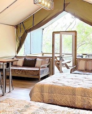 Une pièce aménagée avec une tente, un lit, une table et une chaise.