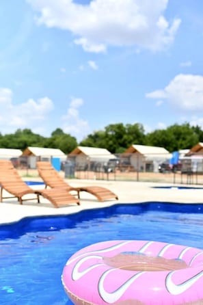 Una piscina con sillas de descanso y un flotador inflable rosa.