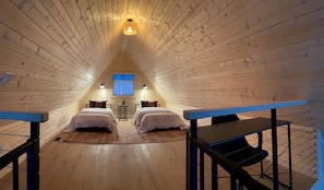Une pièce aux murs en bois, avec deux lits, une fenêtre et un luminaire.