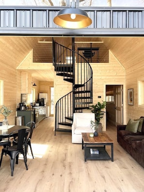 Un loft spacieux doté d’un escalier central en colimaçon, de planchers en bois et d’un coin repas avec une table et des chaises.