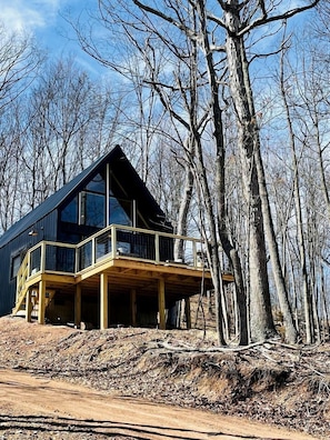 A modern wooden cabin with a balcony, surrounded by trees. - Gorgeous A-Frame Cabin Nestled in the Trees near Lost River, West Virginia (Mathias)