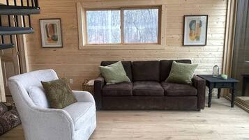 A living room with a sofa, armchair, and a small table with a candle.