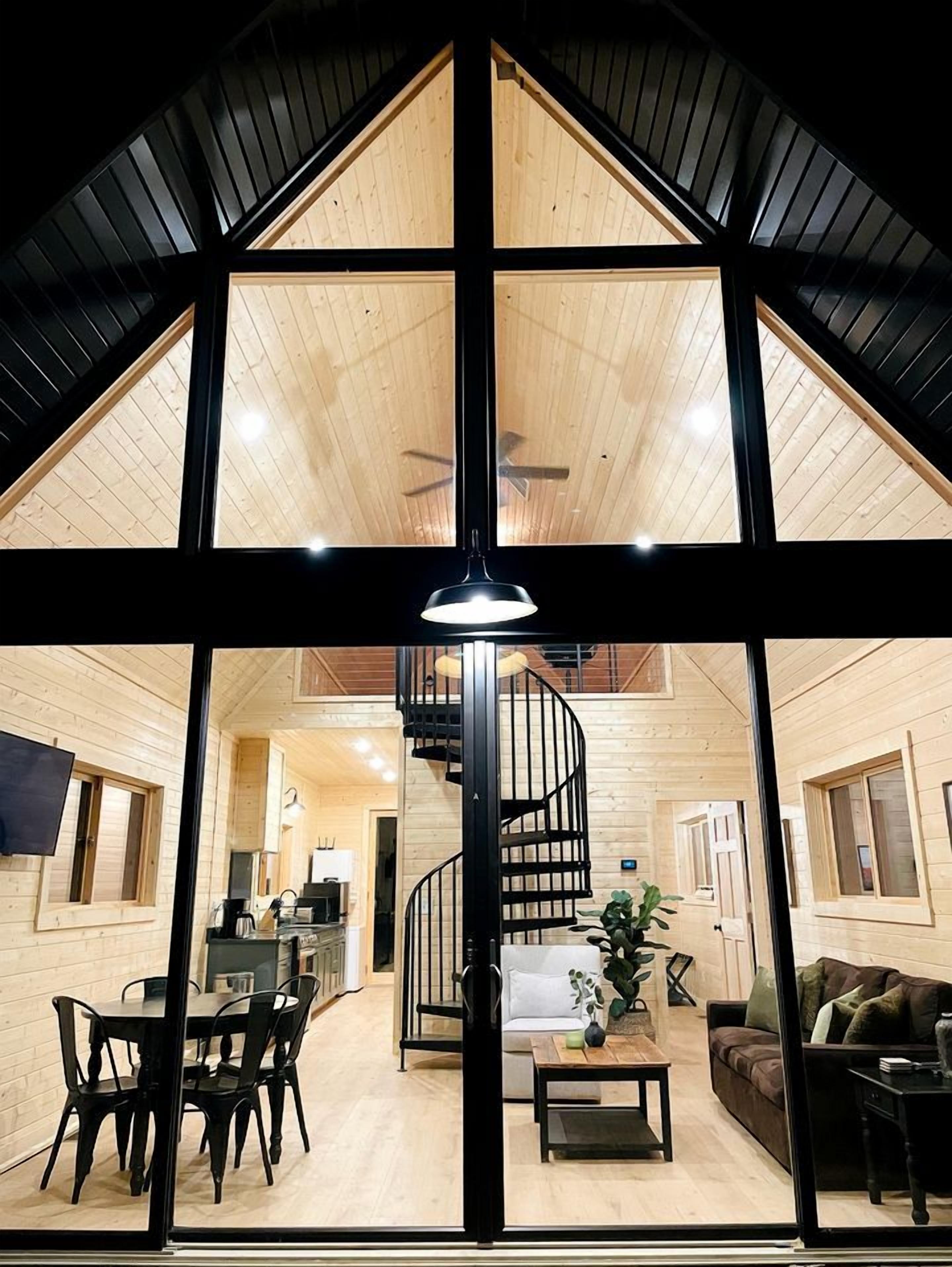 A spacious interior with a central spiral staircase, wooden walls, and a dining area.