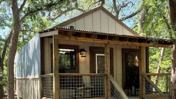 En stuga av trä med en veranda, en trappa och ett inhägnat område.