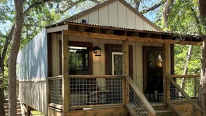 Eine Holzhütte mit Veranda, Treppe und umzäunter Fläche.