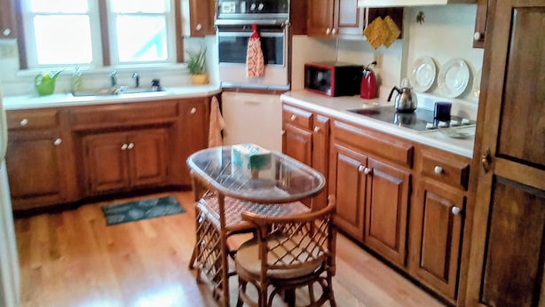 A kitchen with wooden cabinets, a glass-top table, and a built-in oven. - Homestead on Mill St. (Woolrich)