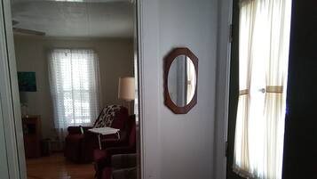 A hallway leading to a living room with a sofa, a lamp, and a mirror on the wall.
