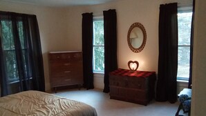 A bedroom with a bed, dresser, vanity, and windows. - Homestead on Mill St. (Woolrich)