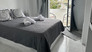 Une chambre à coucher avec un lit, des oreillers, une fenêtre et une vue sur l’extérieur.