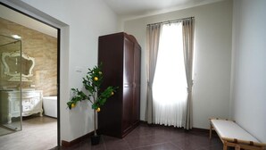 A room with a wooden wardrobe, a bench, a potted plant, a glass shower enclosure, and a view of a bathroom with a mirror. - La Villa des Chien (Sattahip)