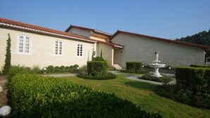 A building with a tiled roof, a fountain, and well-maintained hedges. - La Villa des Chien (Sattahip)