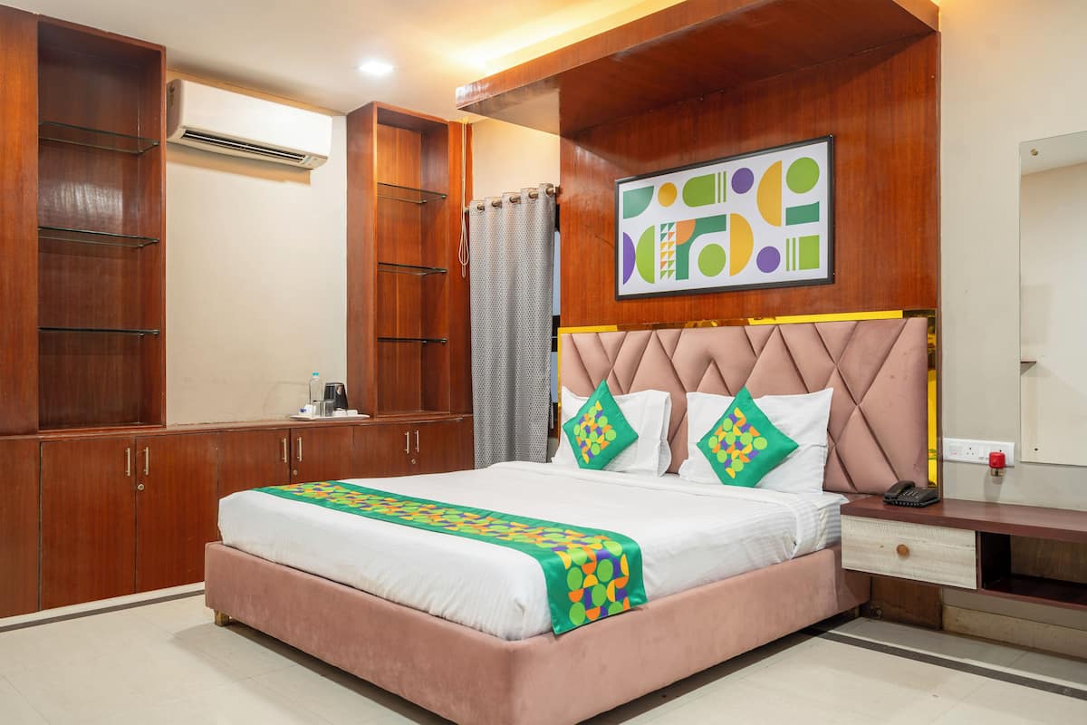 Une chambre d’hôtel comprenant un lit, une armoire en bois, un appareil de climatisation et un élément décoratif mural.