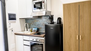 A compact kitchen with a microwave, coffee maker, oven, and a refrigerator.