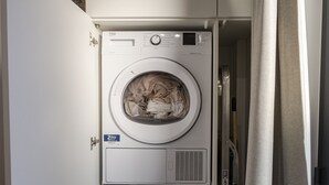 A front-loading washing machine with a control panel, a door, and a curtain partially covering the entrance.