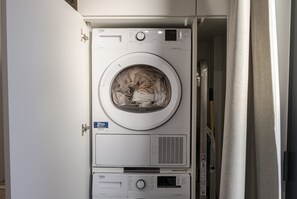 Un lave-linge à chargement frontal doté d’un panneau de commande, d’une porte et d’un rideau qui recouvre partiellement l’ouverture.