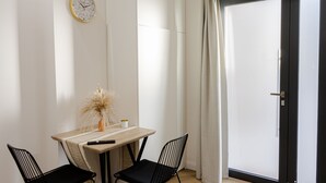 A room with a wooden table, two black chairs, a clock on the wall, and a door with curtains. - Suite with Private Jacuzzi in Catania short and long stays with full kitchen facilities (Catania)
