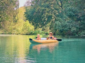 A kayak on a calm body of water with dense greenery in the background.