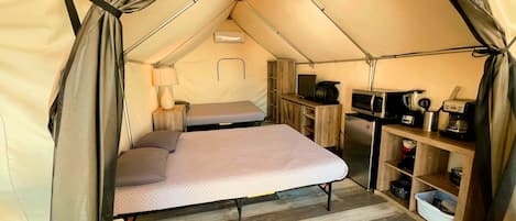 Una tienda de campaña con cama, kitchenette y una pequeña mesa.